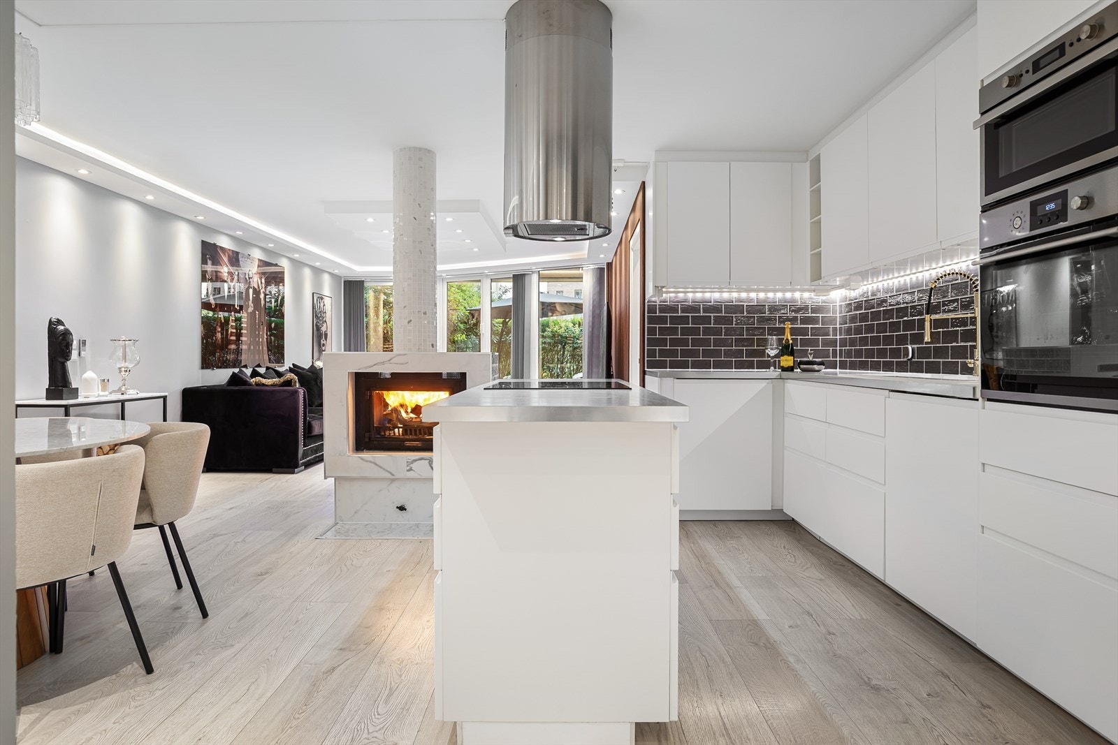 Den sentralt plasserte peisen med glassfelt på to sider fungerer som en naturlig romdeler. Galleribilde