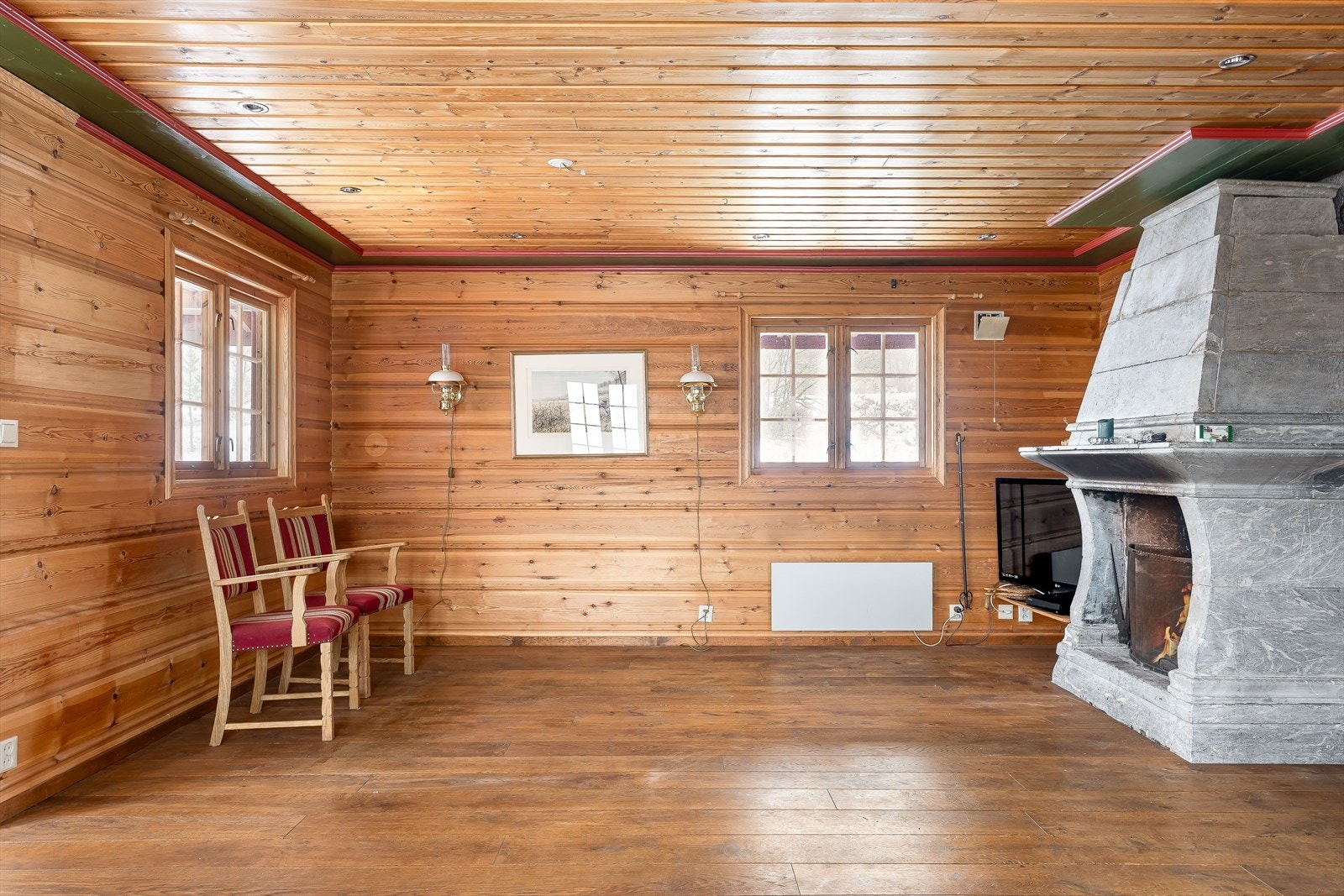 Stuen har en massiv, åpen klebersteinspeis som sammen med vedovnen i bakkant sørger for god varme og den rette hyttekosen! Galleribilde