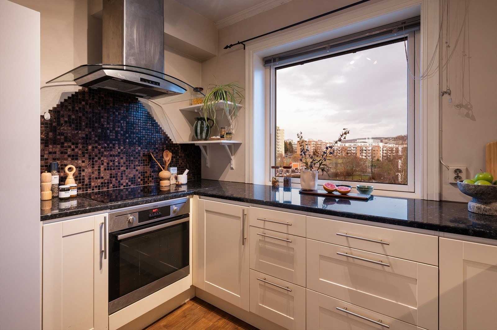 Flotte fliser over benkeplate, samt kjøkkenventilator over kokeplass. Galleribilde