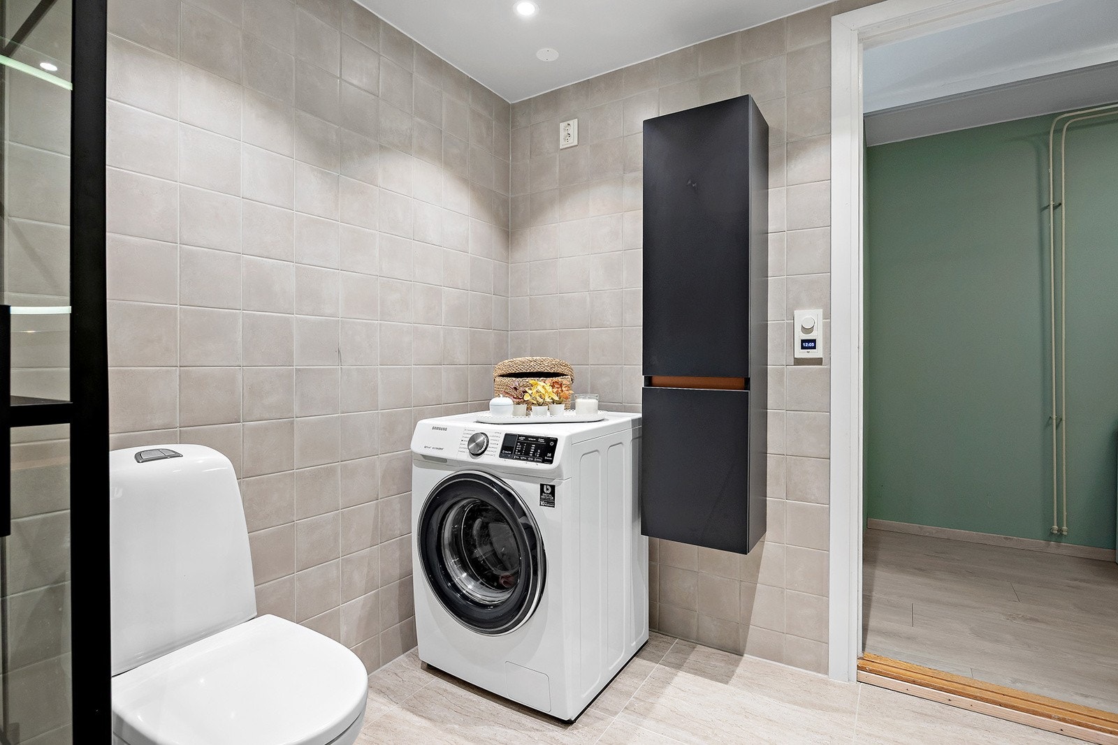 Baderomsinnredningen er bestående av servant med skuffeseksjon, speil med lys, gulvmontert klosett, dusjhjørne med fast glassvegg og svingbar glassdør, opplegg for vaskemaskin. Galleribilde