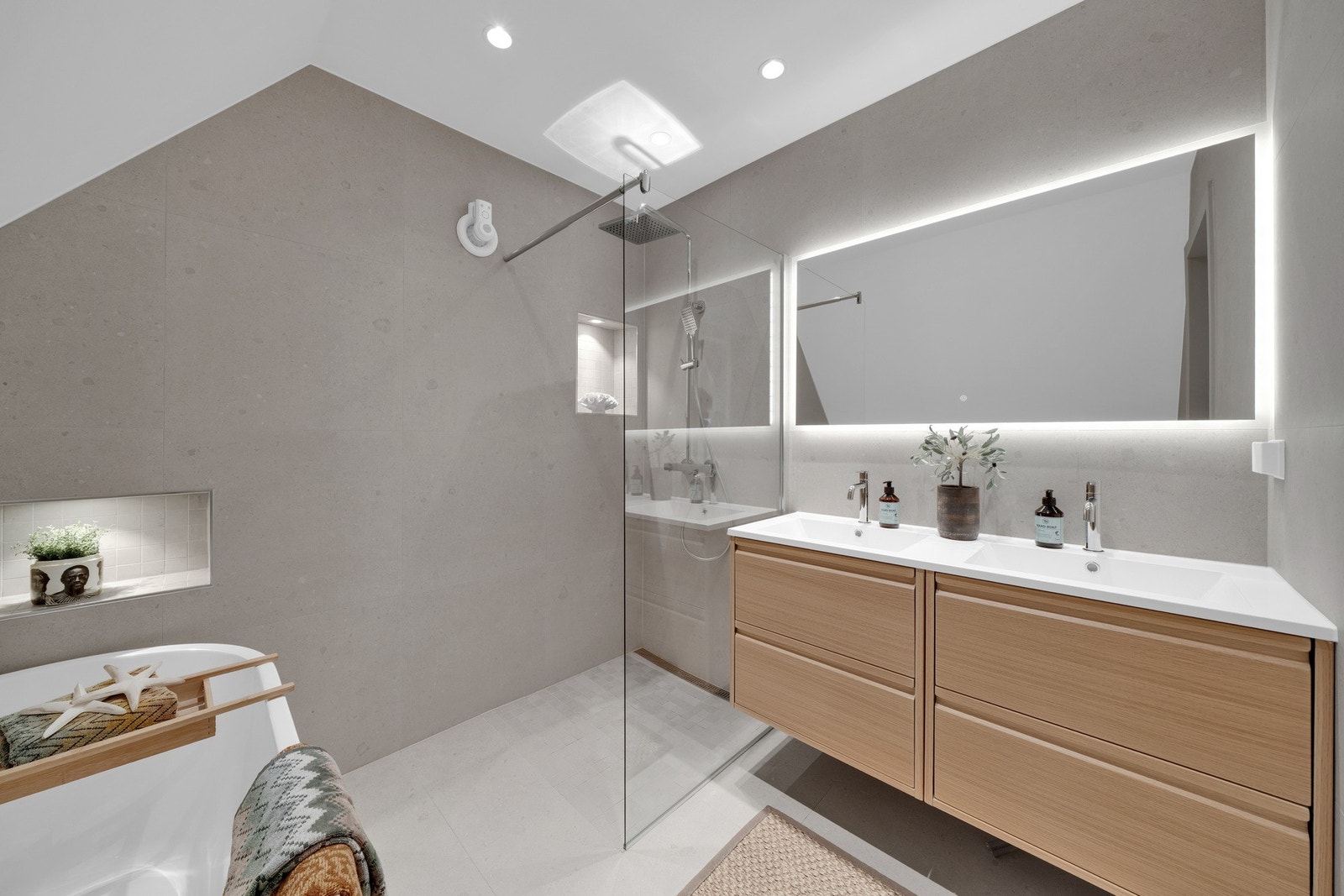 Badet er utstyrt med dusjsone med glassvegg, innbydende armaturer, dobbel servant med lekker innredning Galleribilde