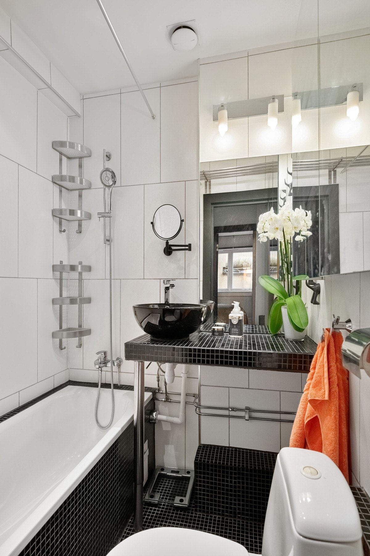 Flislagt bad med innmurt badekar, plassbygd innredning og speilskap. Galleribilde