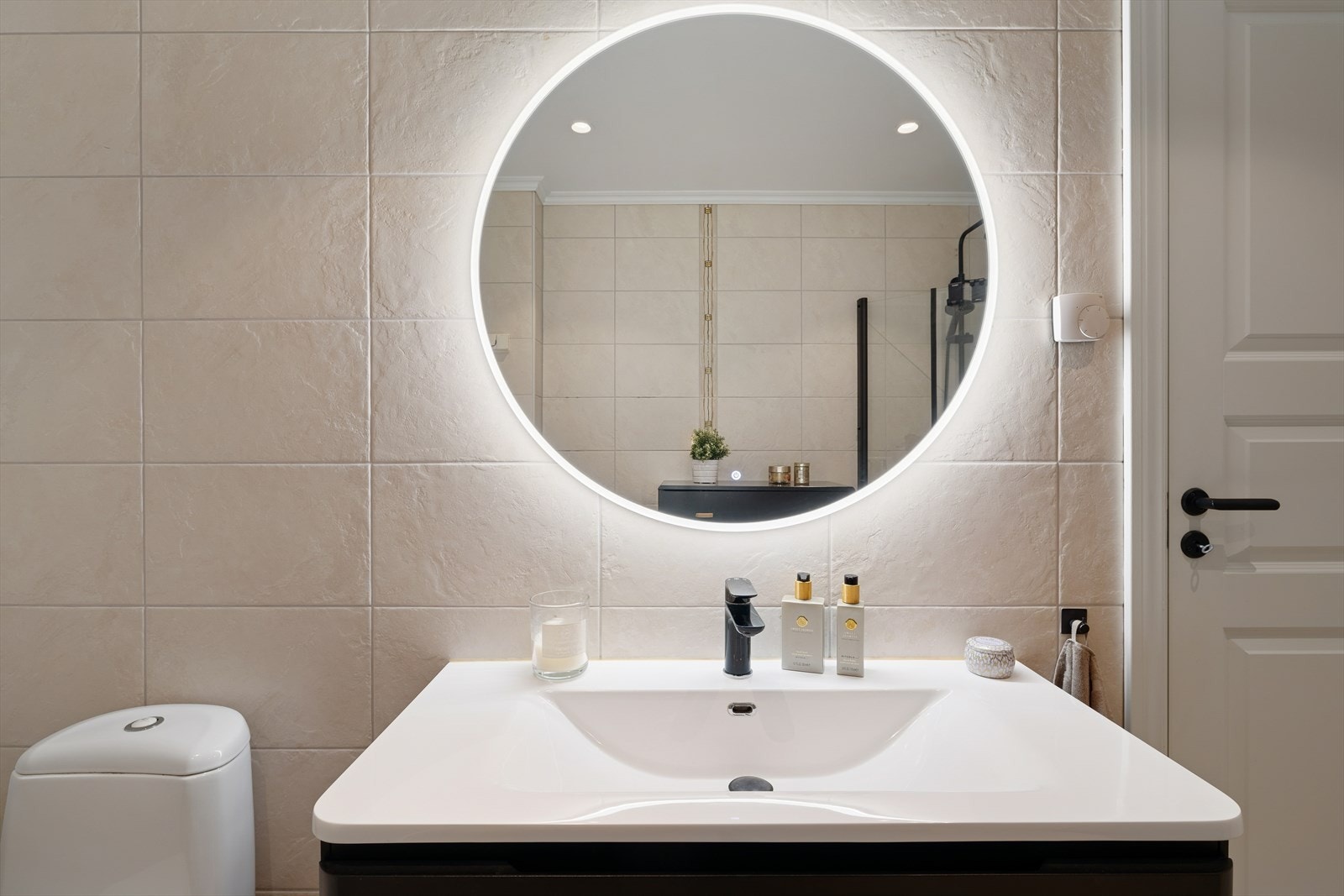 Det er utstyrt med en mørk servantinnredning, wc på sokkel, opplegg for vaskemaskin og dusjhjørne med glassdører. Galleribilde