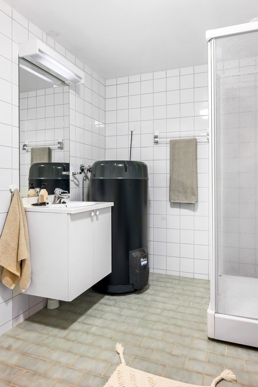 Rommet er utstyrt med dusjkabinett, veggmontert utslagsvask, servantskap, speil og røropplegg for vaskemaskin. Varmtvannsbereder av nyere dato er plassert innerst i hjørnet. Galleribilde