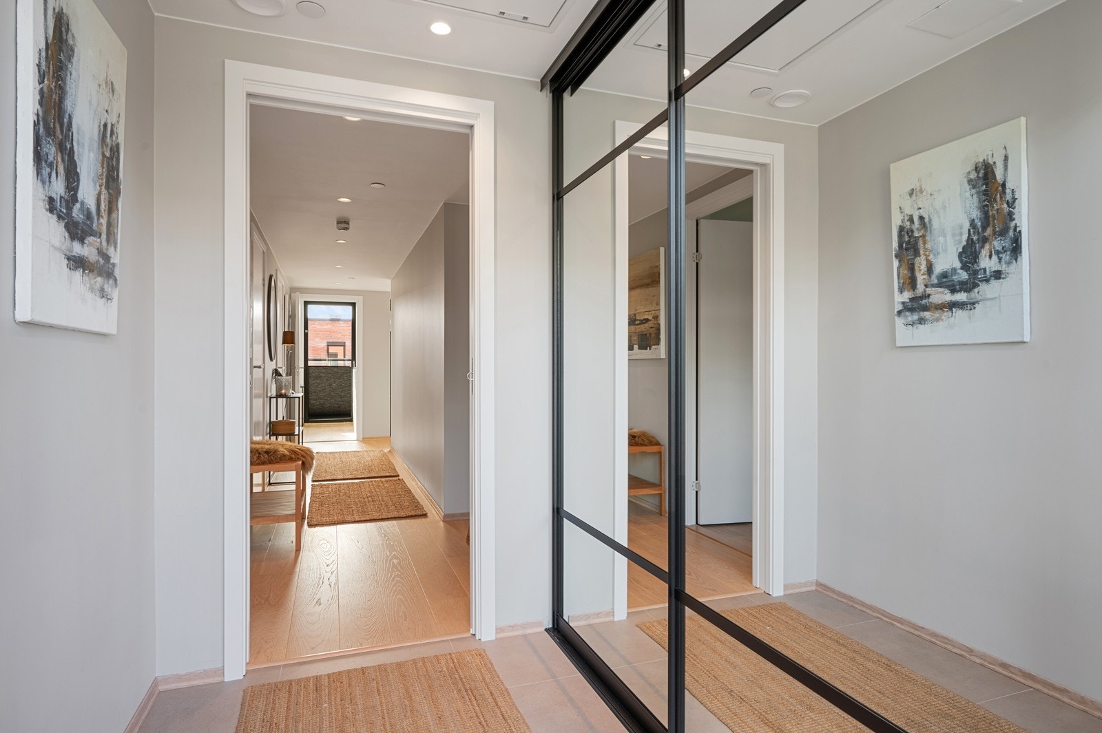 Entré. Her er det en praktisk skyvedørsgarderobe med glassfronter. Det er fliser i gangen og skyvedør videre inn til leiligheten Galleribilde