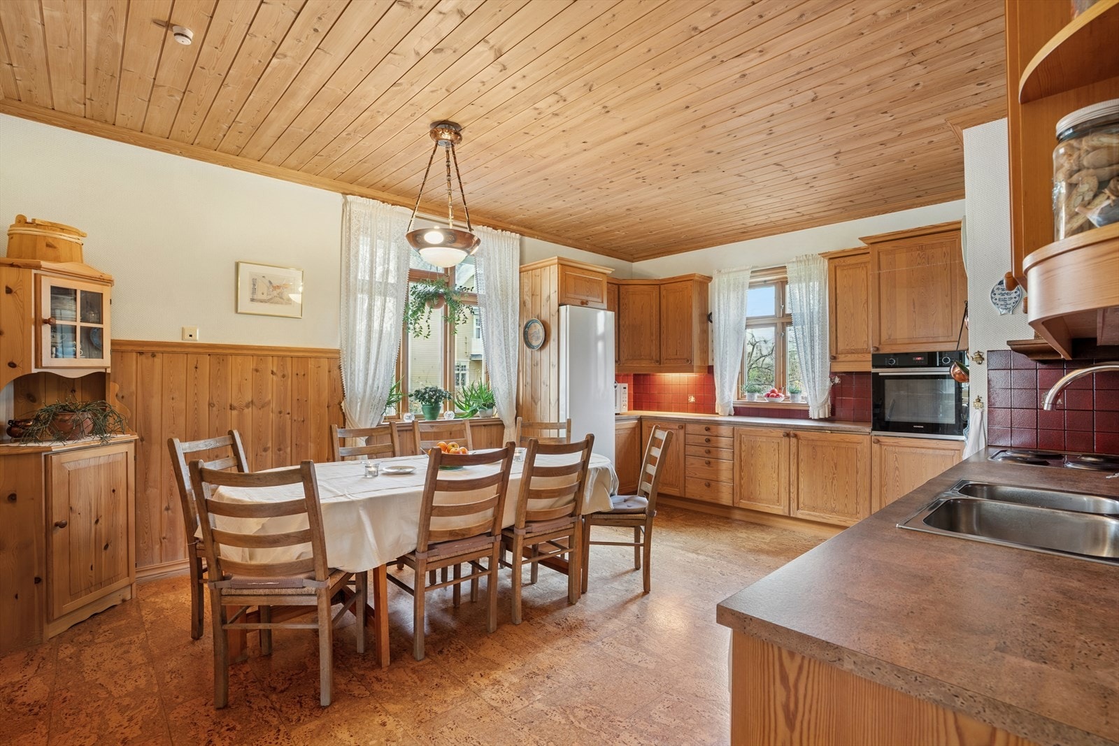 Romslig kjøkken med innredning med profilerte fronter og benkeplate i laminat utførelse. Galleribilde