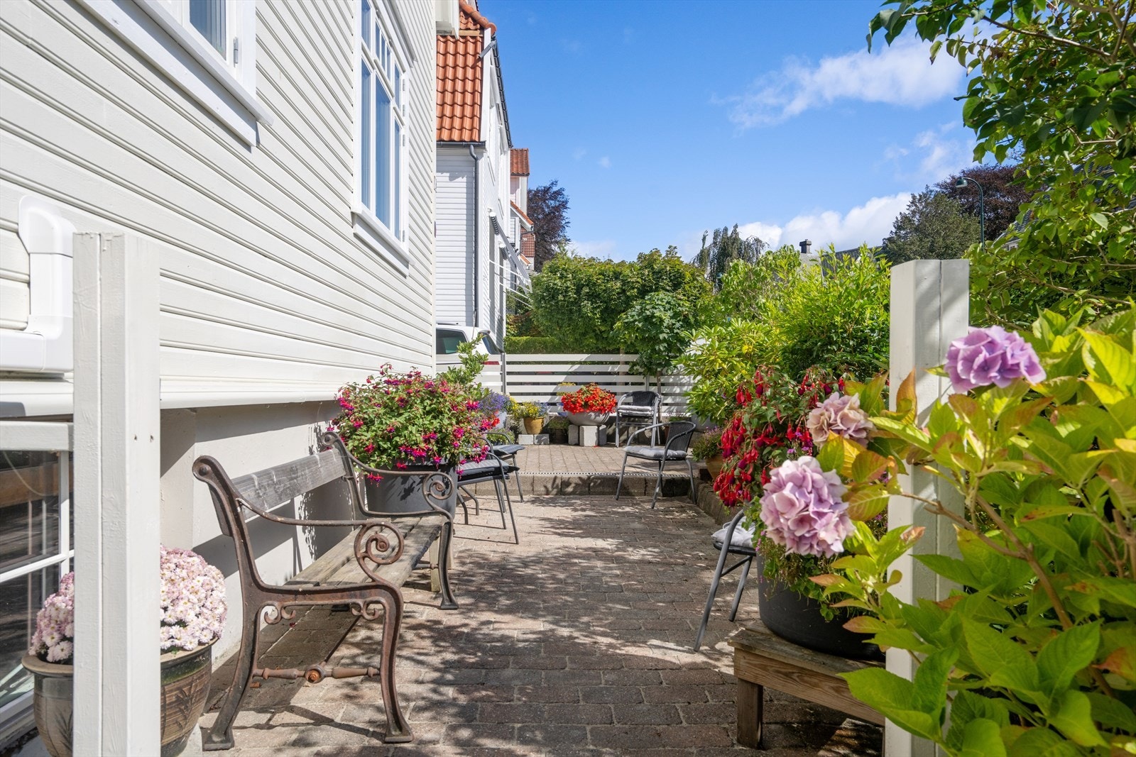 Nydelig uteområde omkranset av frodig beplantning. Området er ideelt for avslapning og samvær, med enkel tilgang fra boligens inngangsparti. Galleribilde