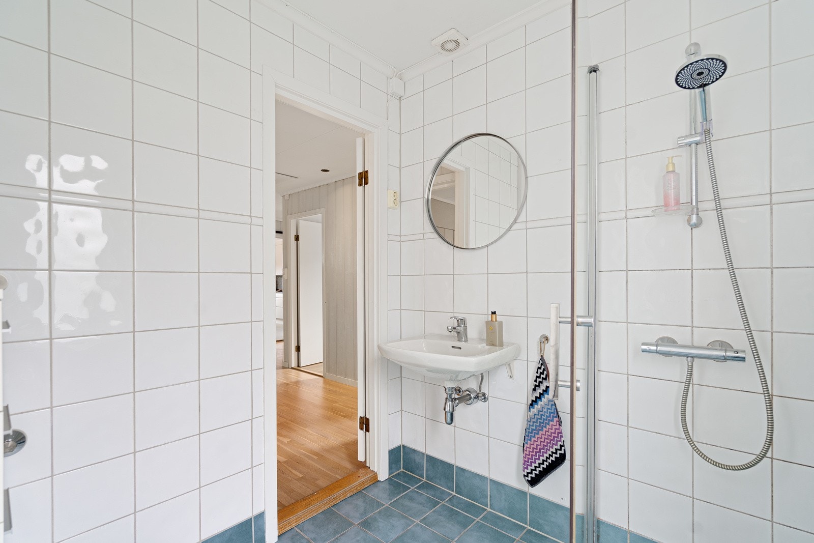 Flislagt bad med lyse fliser på vegg og blått på gulv som gir en fin kontrast Galleribilde