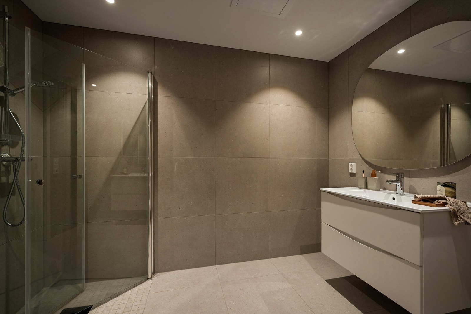 I samme etasje som soverommene inngår også hovedbadet. Gulv og vegger er utført med like storformat fliser som fremmer helhet. Galleribilde