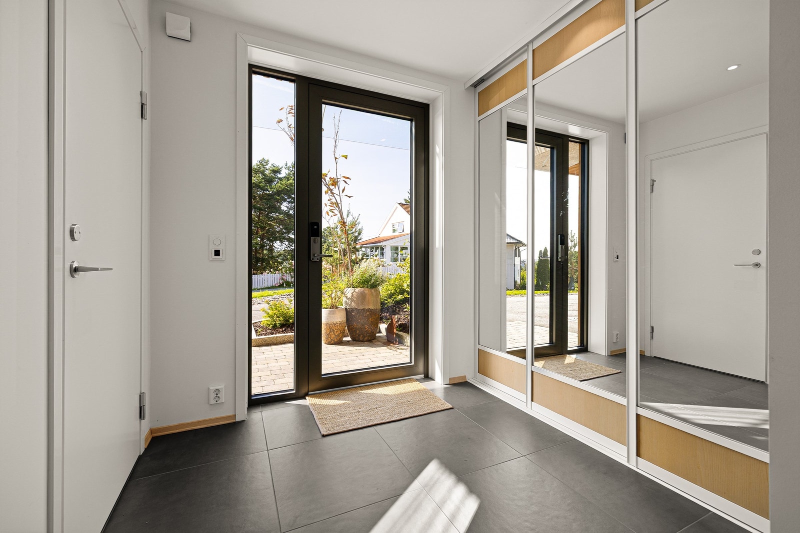 Glass i inngangsdør og sidefelt fyller den romslige hallen med naturlig lys. Elektronisk kodelås gjør nøkler overflødige. Galleribilde