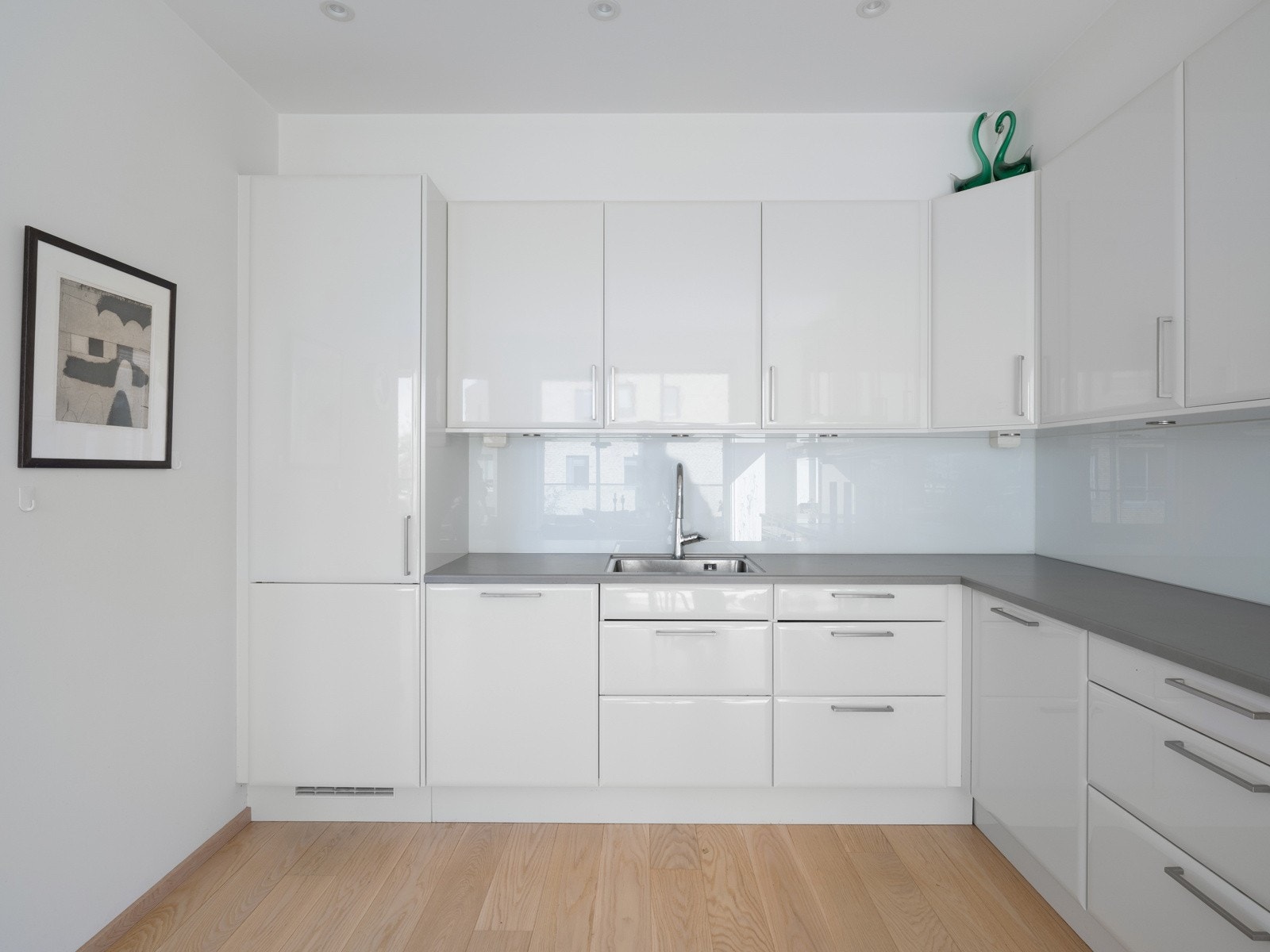 Kjøkkenet har en tidløs utforming med hvite, slette fronter som gir et rent og moderne uttrykk. Galleribilde