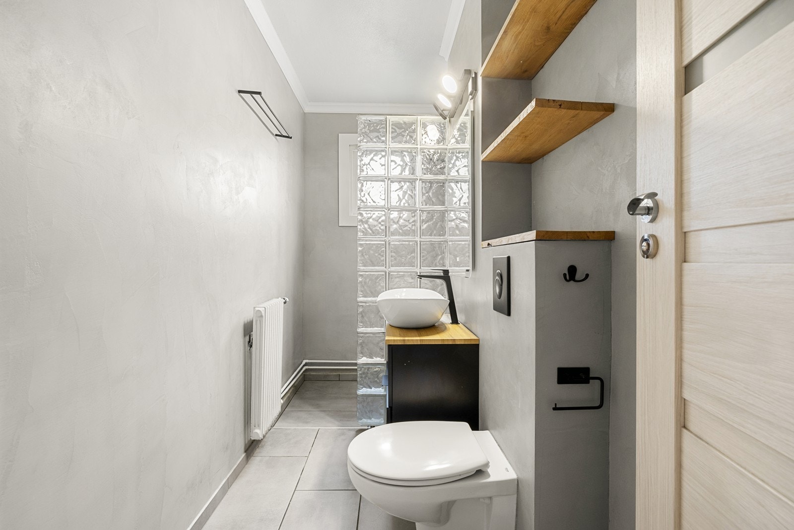 Badet er overflateoppusset i 2024 med microsement på veggene og fliser på gulvet. Varmekilden er fra vegghengt radiator. Galleribilde