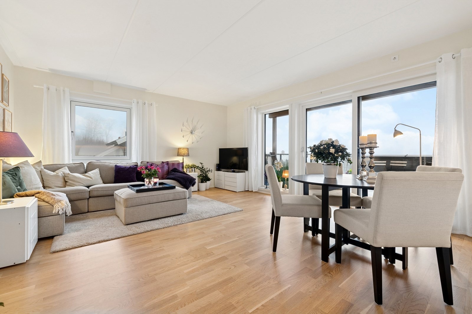 Stue med store vindusflater som slipper inn mye naturlig lys. Her er det plass til både sofagruppe og spisegruppe. Galleribilde