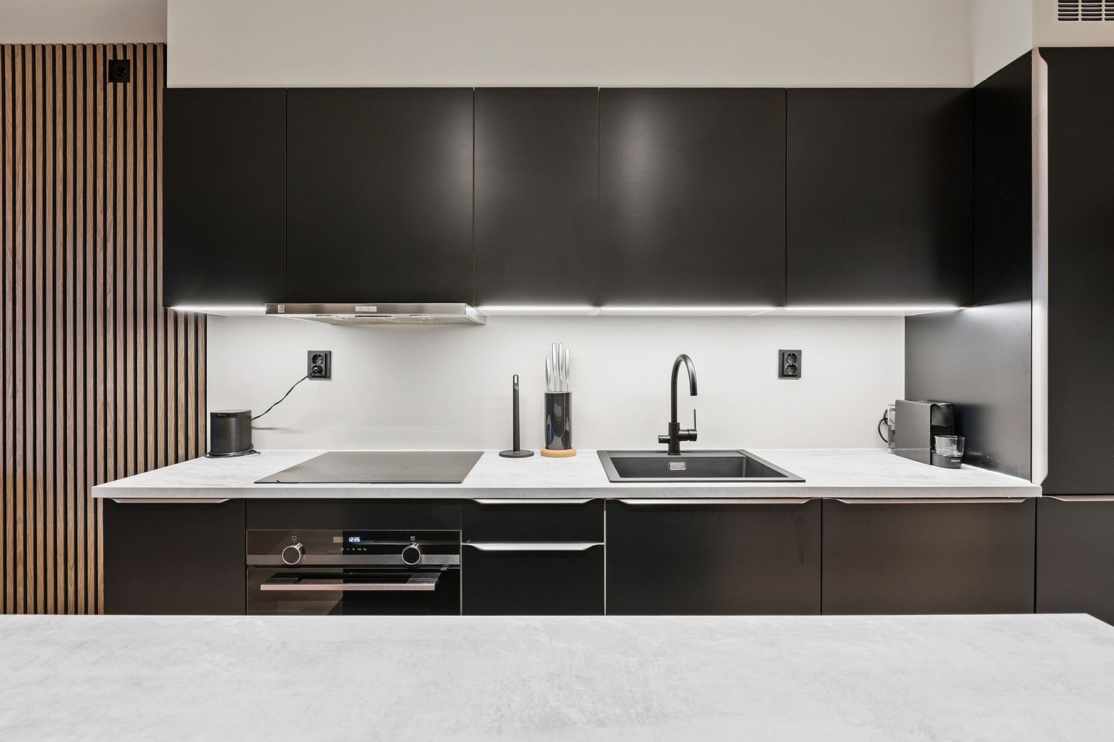 Moderne kjøkken med glatte fronter, integrerte hvitevarer og en praktisk kjøkkenøy. Galleribilde