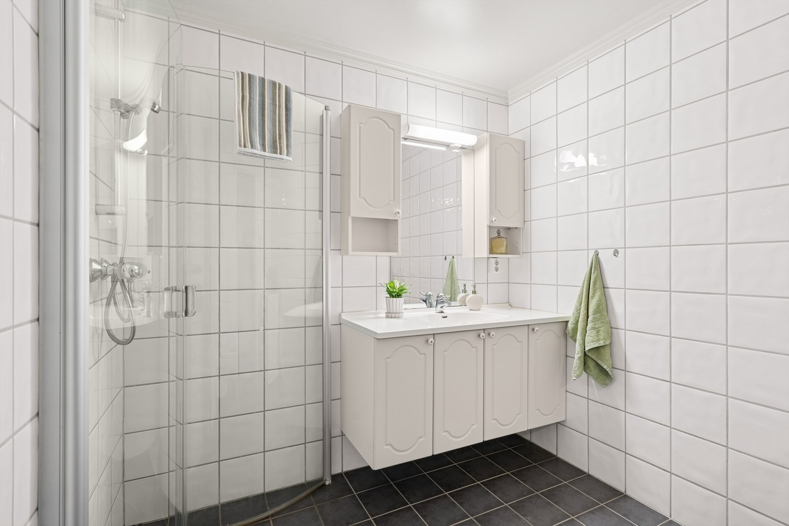 Badet har innredning med nedfelt servant, vegghengt toalett og dusjhjørne med glassvegger. Galleribilde