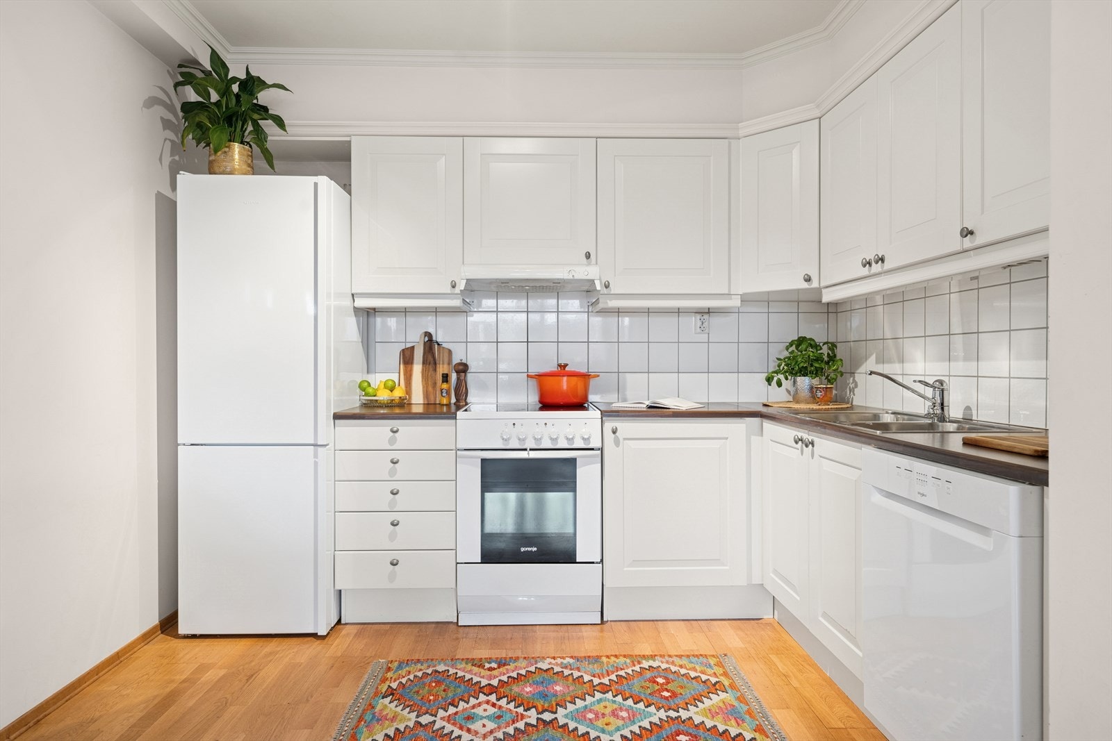 Kjøkkenet har stilfrie og hvite profilerte fronter og benkeplate i høytrykkslaminat. Galleribilde