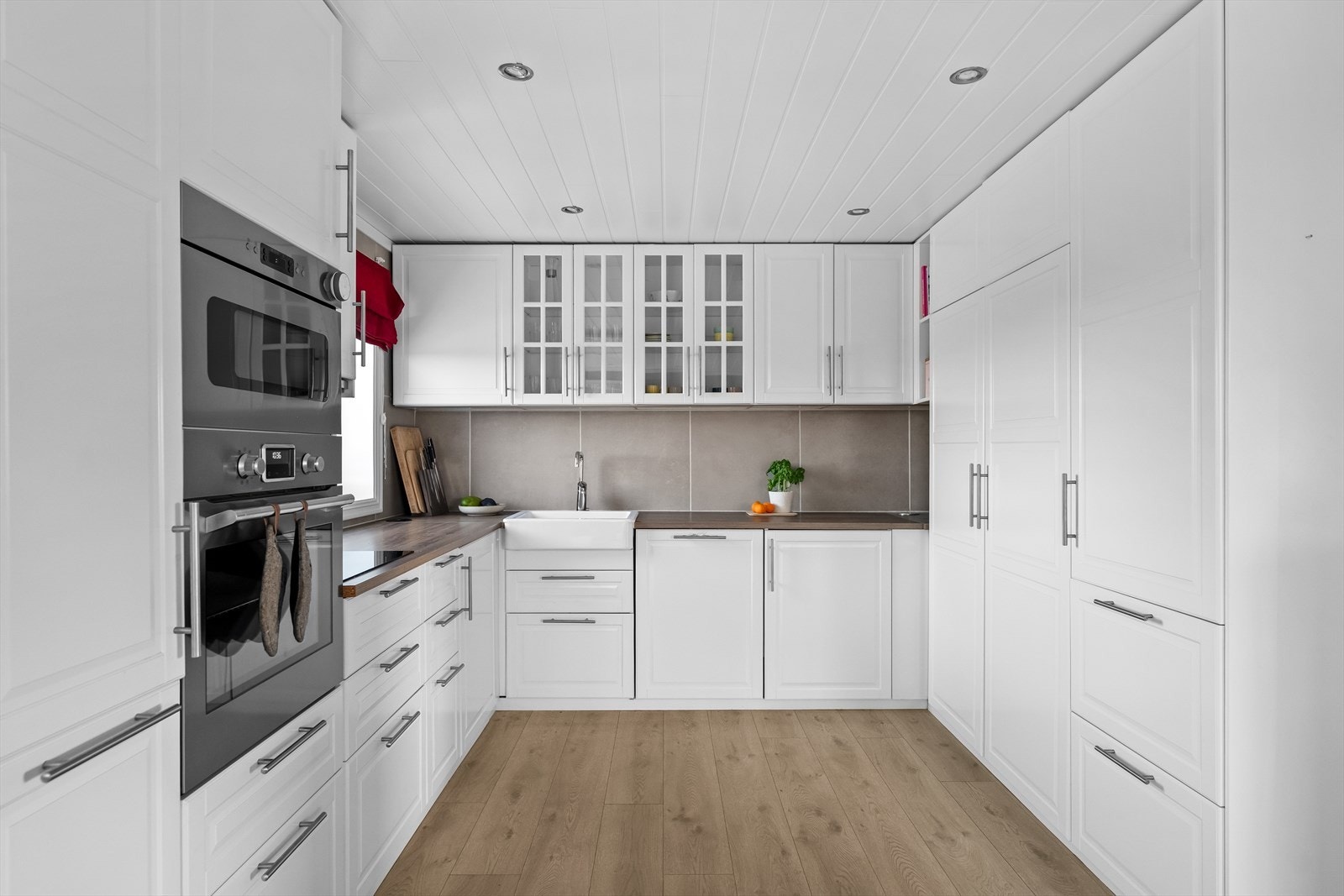 Tidløst kjøkken fra 2018 med profilerte fronter, integrerte hvitevarer og benkeplate i laminat. Galleribilde