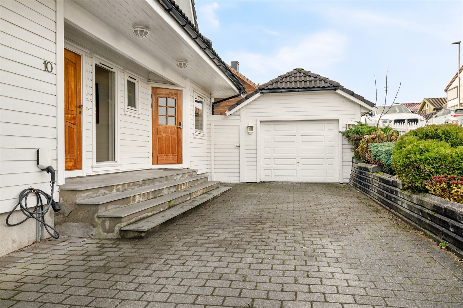 Tomten er godt utnyttet med en stor steinbelagt innkjørsel, garasje og fine uteplasser. Galleribilde