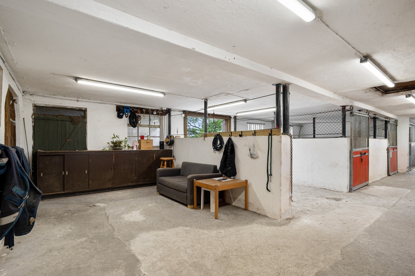 Driftsbygning - 7 stallplasser, gang med servant og åpning/dør ut for dyrene. Galleribilde