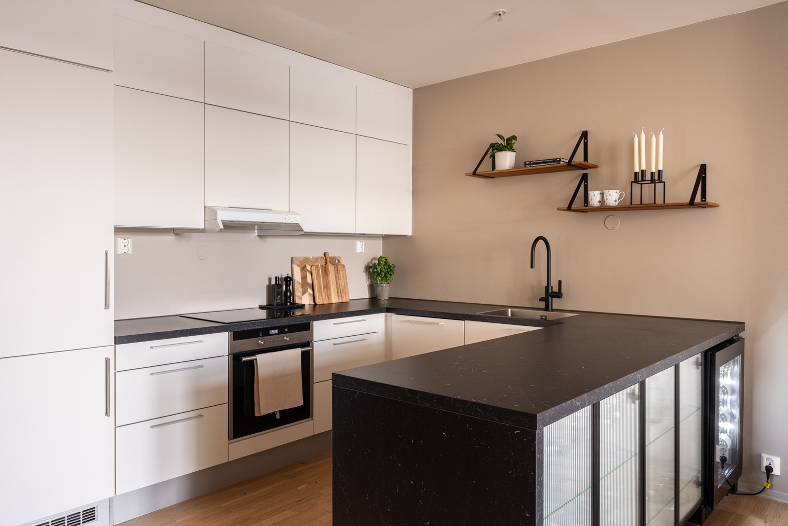 Moderne og innbydende kjøkken med god skapplass, integrerte hvitevarer og sort benkeplate som skaper et moderne uttrykk. Galleribilde