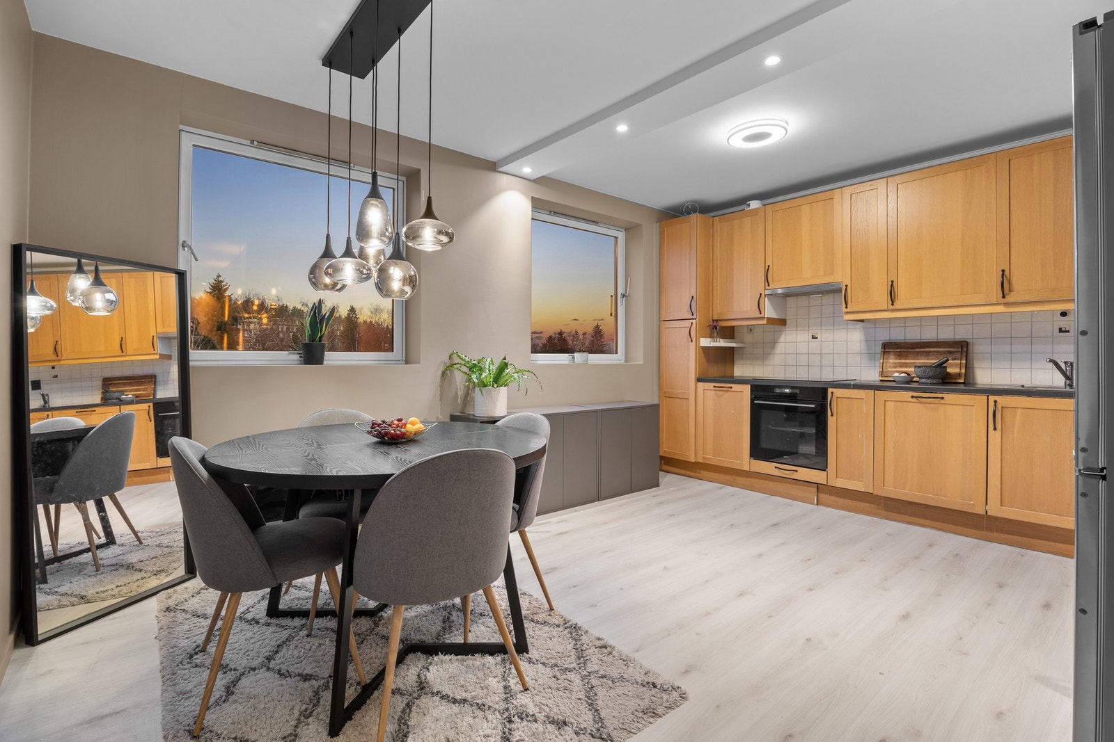 Stilfull kjøkkensone med gode arbeidsflater, moderne belysning og integrerte hvitevarer. Her får du et praktisk oppsett med fliser over benk, laminert benkeplate og nisje for kjøl/frys. Galleribilde