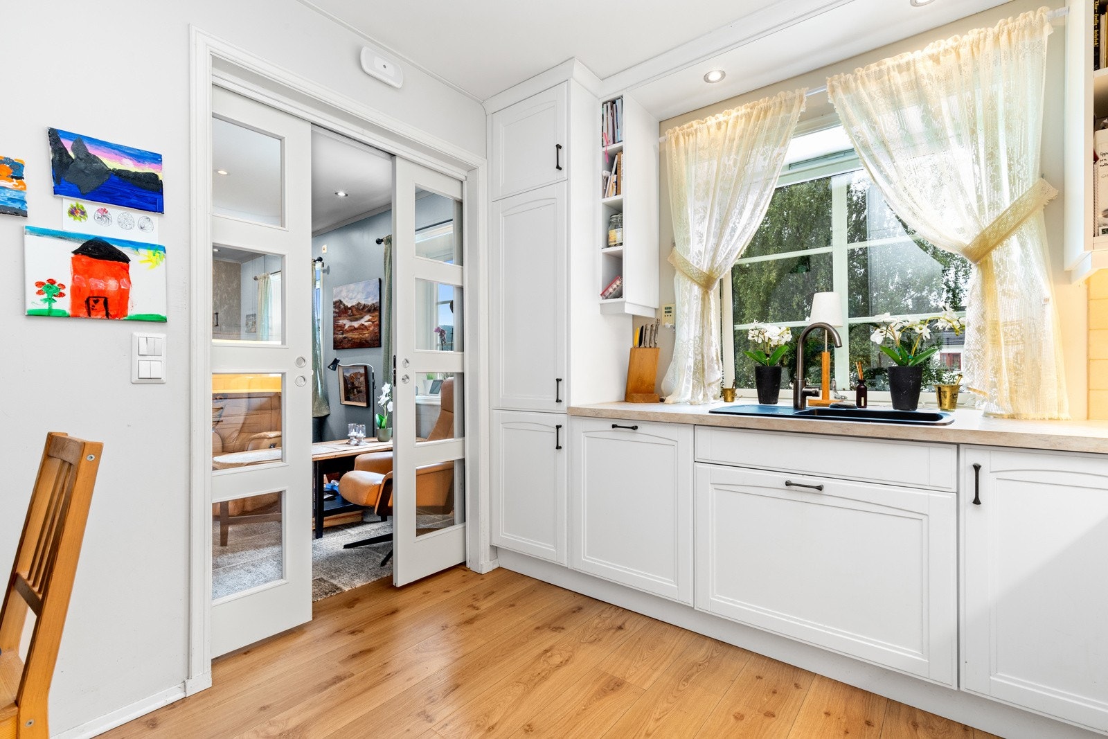 Fra kjøkkenet har man utsikt mot hagen foran og lekeplassen som er anlagt i senter av havebyen. Galleribilde