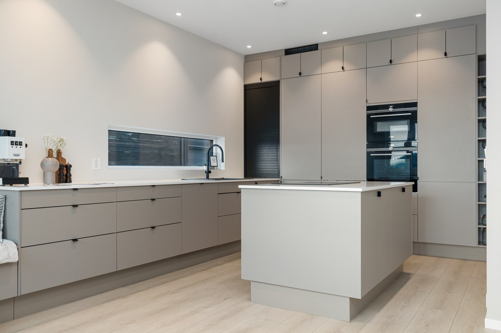Gjennomført og påkostet kjøkken med moderne, slette fronter, god skapplass, kjøkkenøy med stor platetopp, nedfelt ventilator, integrerte hvitevarer med wifi-styring og integrerte Sonos-høyttalere i himlingen. Galleribilde