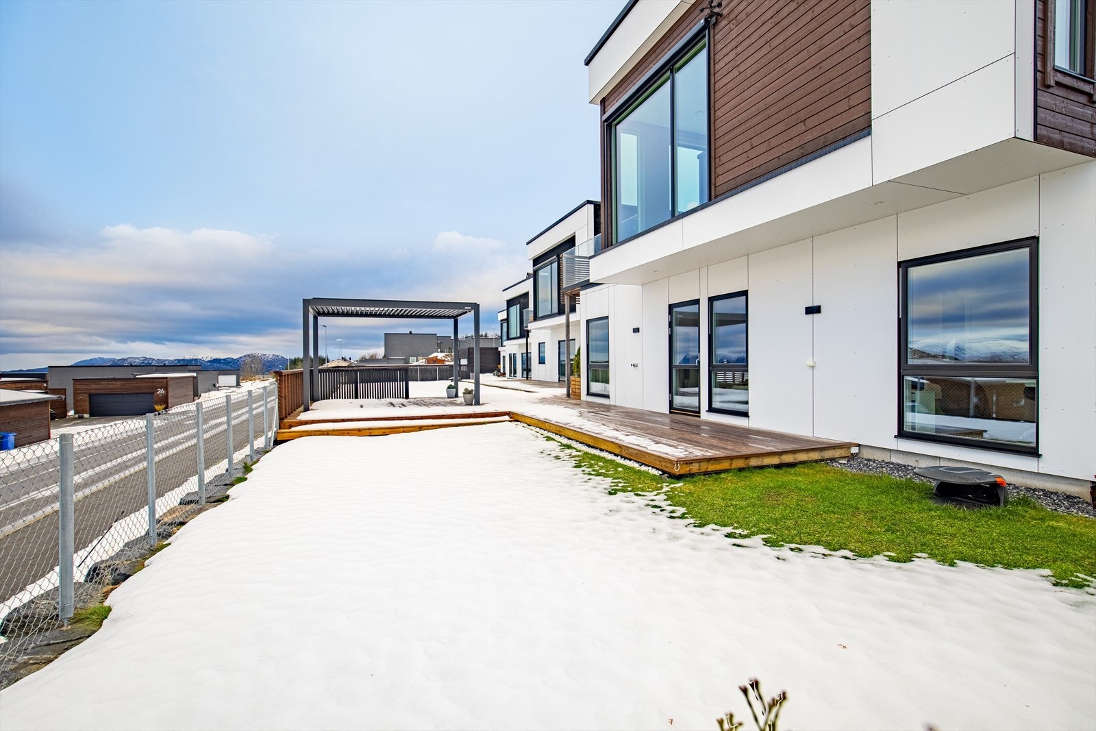 Sørvendt uteområde med hage, stor markterrasse, pergola og trapp til altan og hovedinngang. Galleribilde