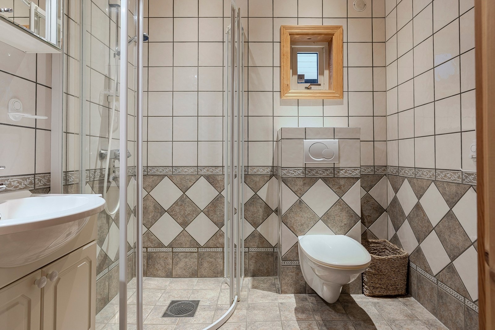 Pent, flislagt baderom innredet med servant, toalett og dusjhjørne. Galleribilde