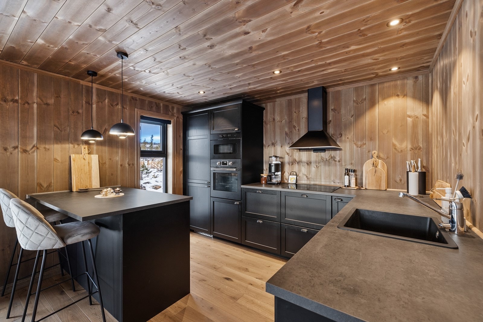 Stilrent kjøkken innredet med profilerte fronter og integrert kjøl/fryseskap platetopp, stekeovn, og oppvaskmaskin. Mekanisk kjøkkenvifte over stekesonen Galleribilde