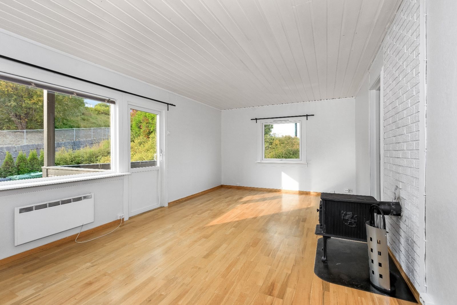 Lys og romslig stue med fin plass til sofa og spisebord. Peisovn og utgang til balkong. Galleribilde