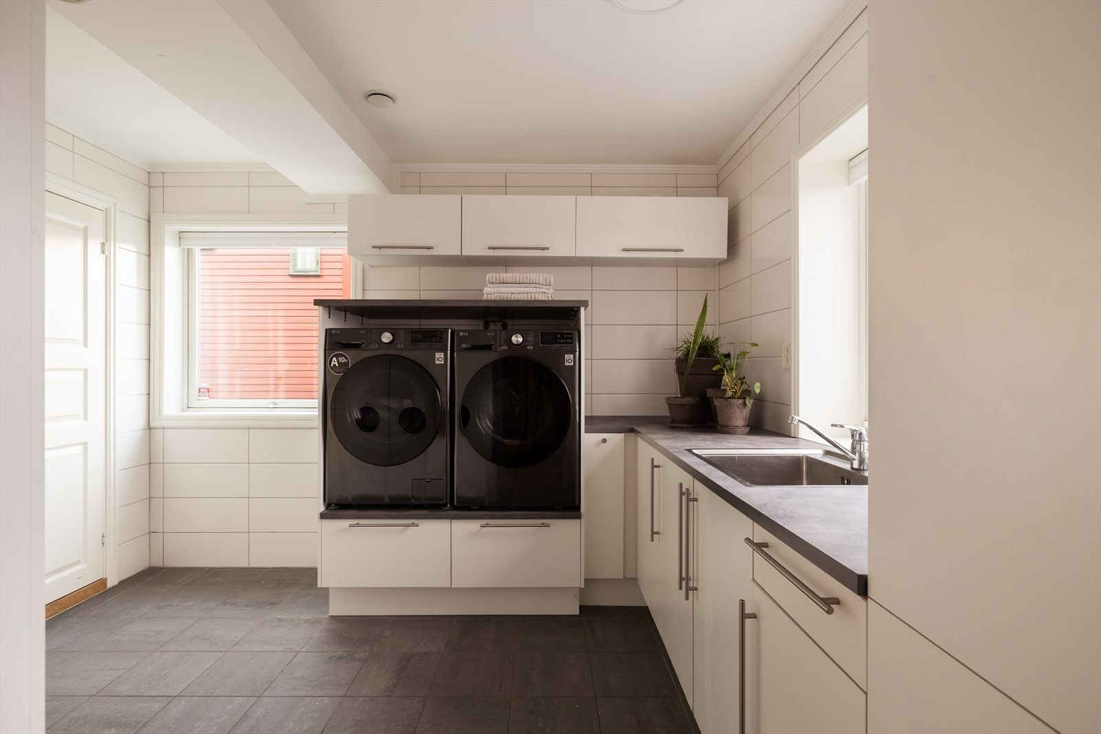 Med direkte adkomst fra entréen får du et praktisk vaskerom, ideelt når familien kommer inn med skitne sko eller våte poter. Rommet er utstyrt med benkeskap, høyskap med glatte fronter, laminert benkeplate og nedfelt stålkum. Galleribilde