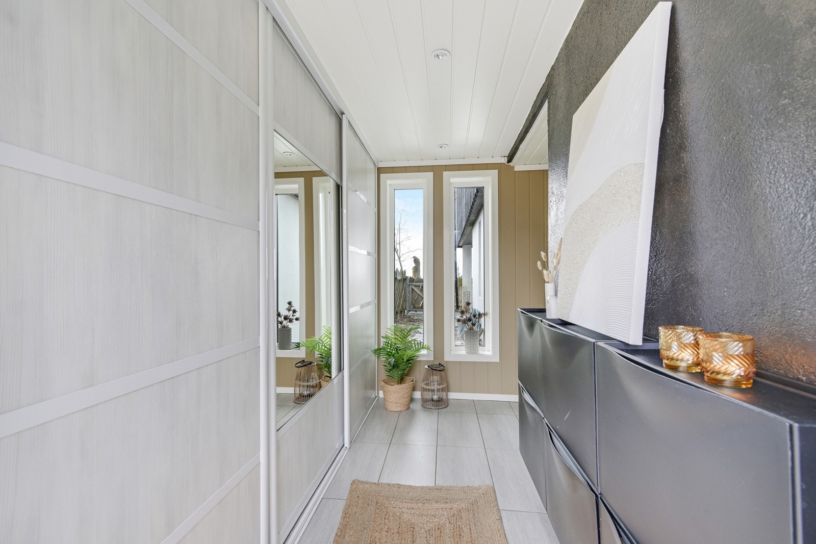 Vi fortsetter på innsiden - flislagt entre med skyvedørsgarderobe Galleribilde