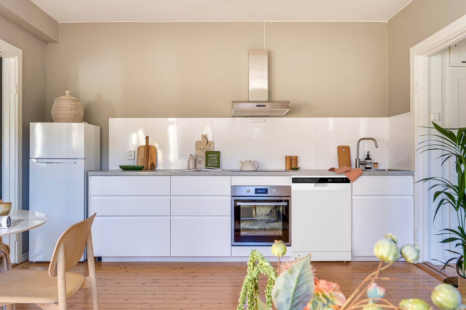 En moderne kjøkkeninnredning med hvite, glatte fronter og benkeplate av laminat. Kjøleskap, kokeplate, ovn medfølger. Oppvaskmaskin digitalt satt inn. Galleribilde