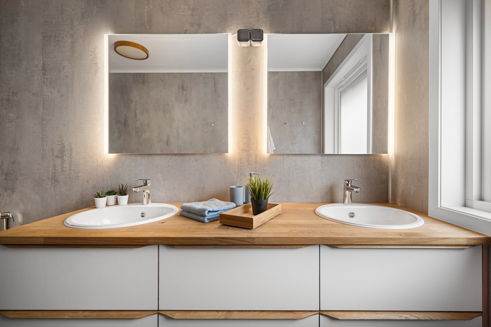 Badet er innredet med dusjkabinett, dobbel servant, speil med lys,lampe i tak, toalett og bide Galleribilde