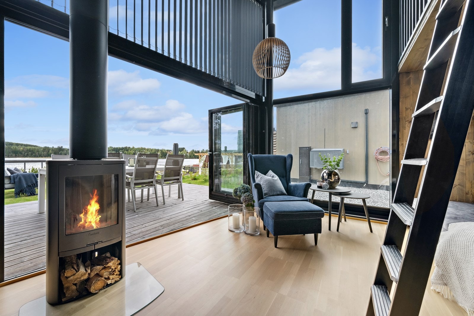 Vinduer fra gulv til tak som skaper en utrolig opplevelse av å få naturen direkte inn i hytta. Foldedøren kan foldes helt sammen slik at stuen forlenges til en del av uterommet. Galleribilde