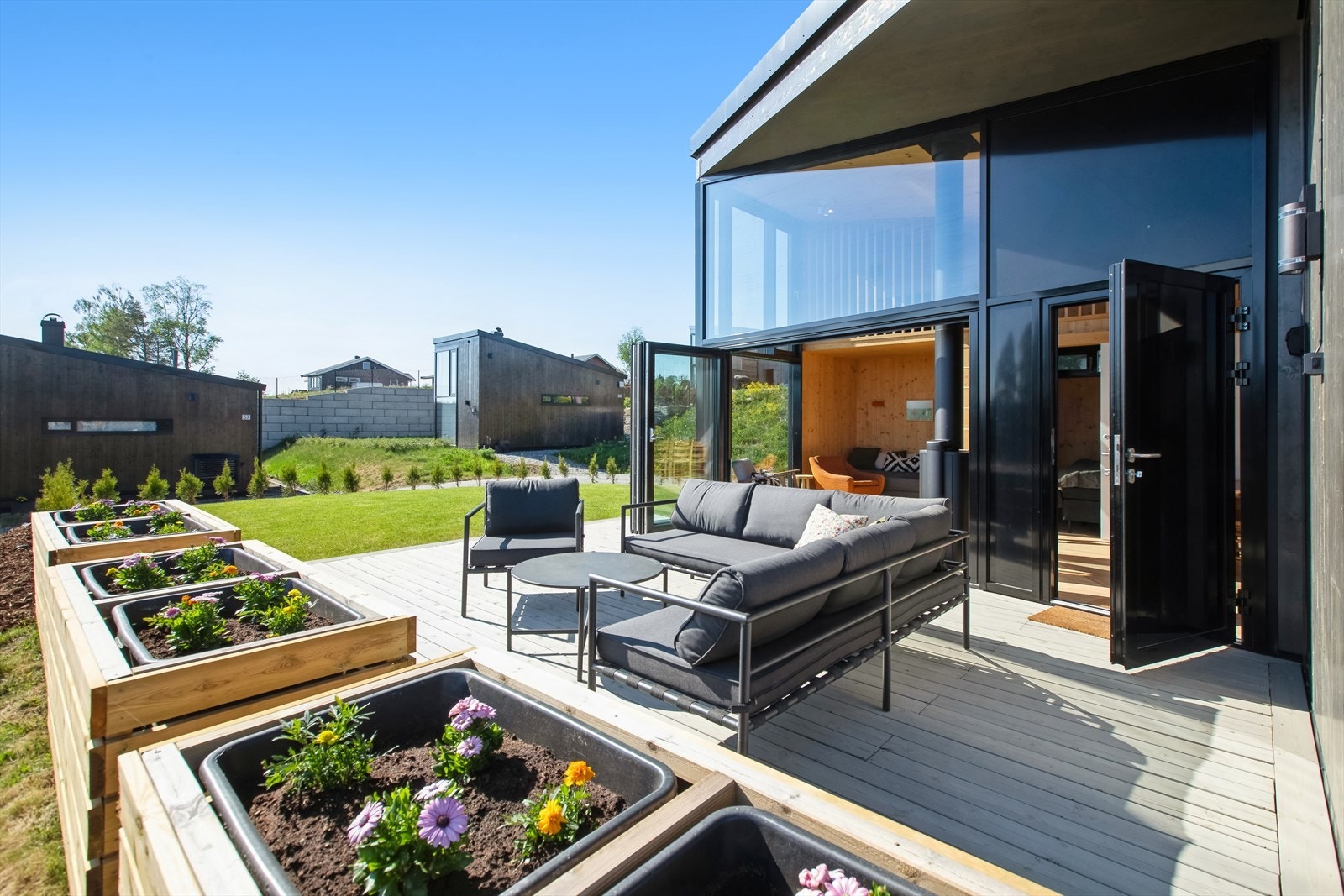 Hjørnetomten er pent opparbeidet med ferdigplen, markterrasse foran hytta samt plantekasser og tujahekk som skaper naturlig skille og hindrer innsyn. Galleribilde