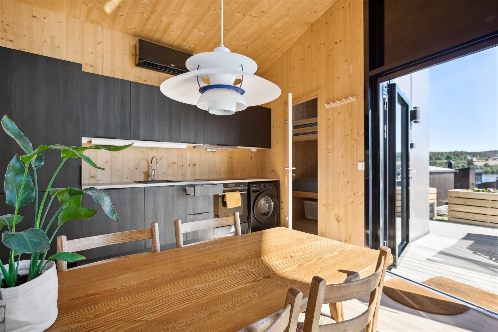 Flott HTH kjøkken med moderne, sort innredning med slette fronter og integrerte hvitevarer. Praktisk og plassbesparende med vaskemaskin på kjøkkenet. Galleribilde