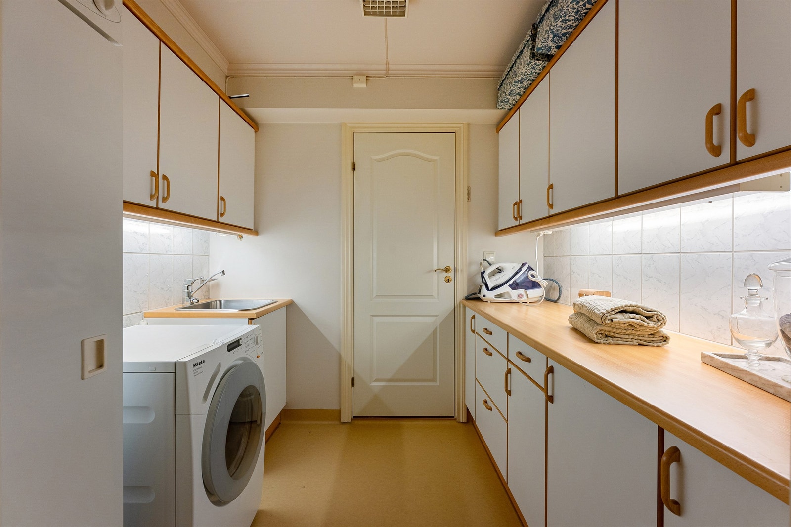 Separat vaskerom med romslig skapinnredning og utslagsvask Galleribilde