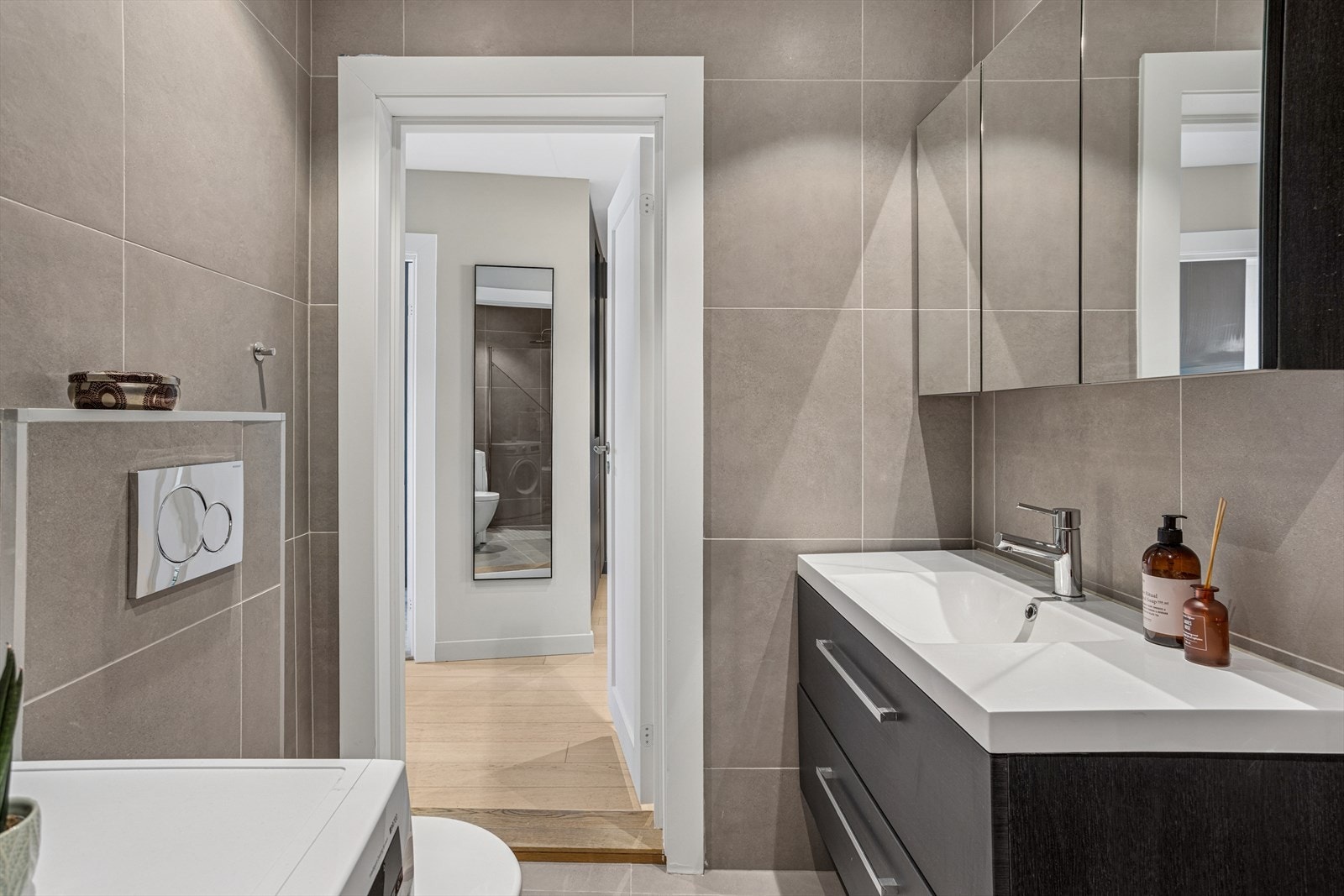 Baderommet består av veggmontert klosett, dusjhjørne med innfellbare dører og en nedfelt servant med tilhørende skuffeinnredning. Fallforholdet på gulvet i bad har forøvrig fått TG1 fra takstmann. Galleribilde