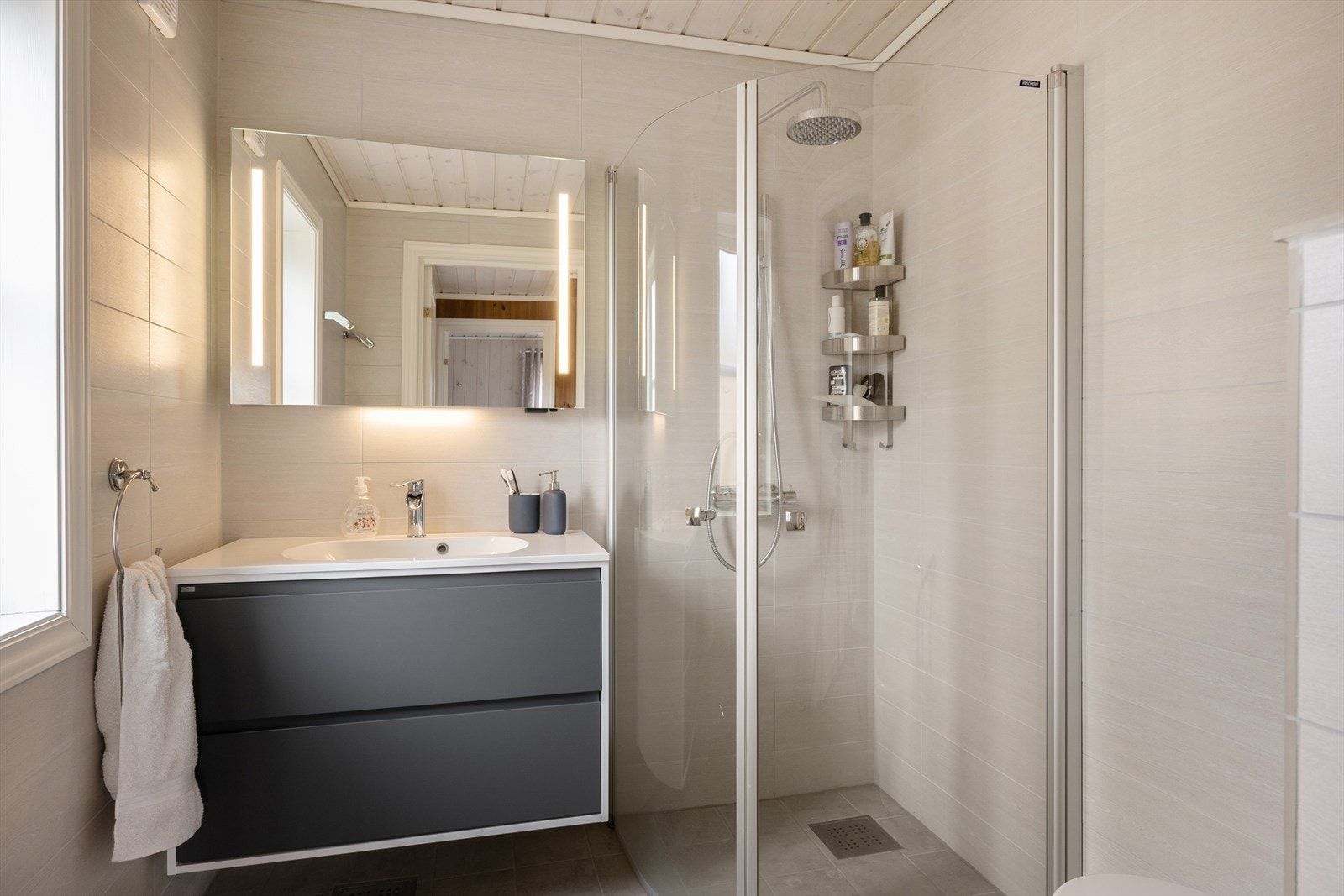 Flott bad med fliser på gulv og vegger, panel i himling. Galleribilde