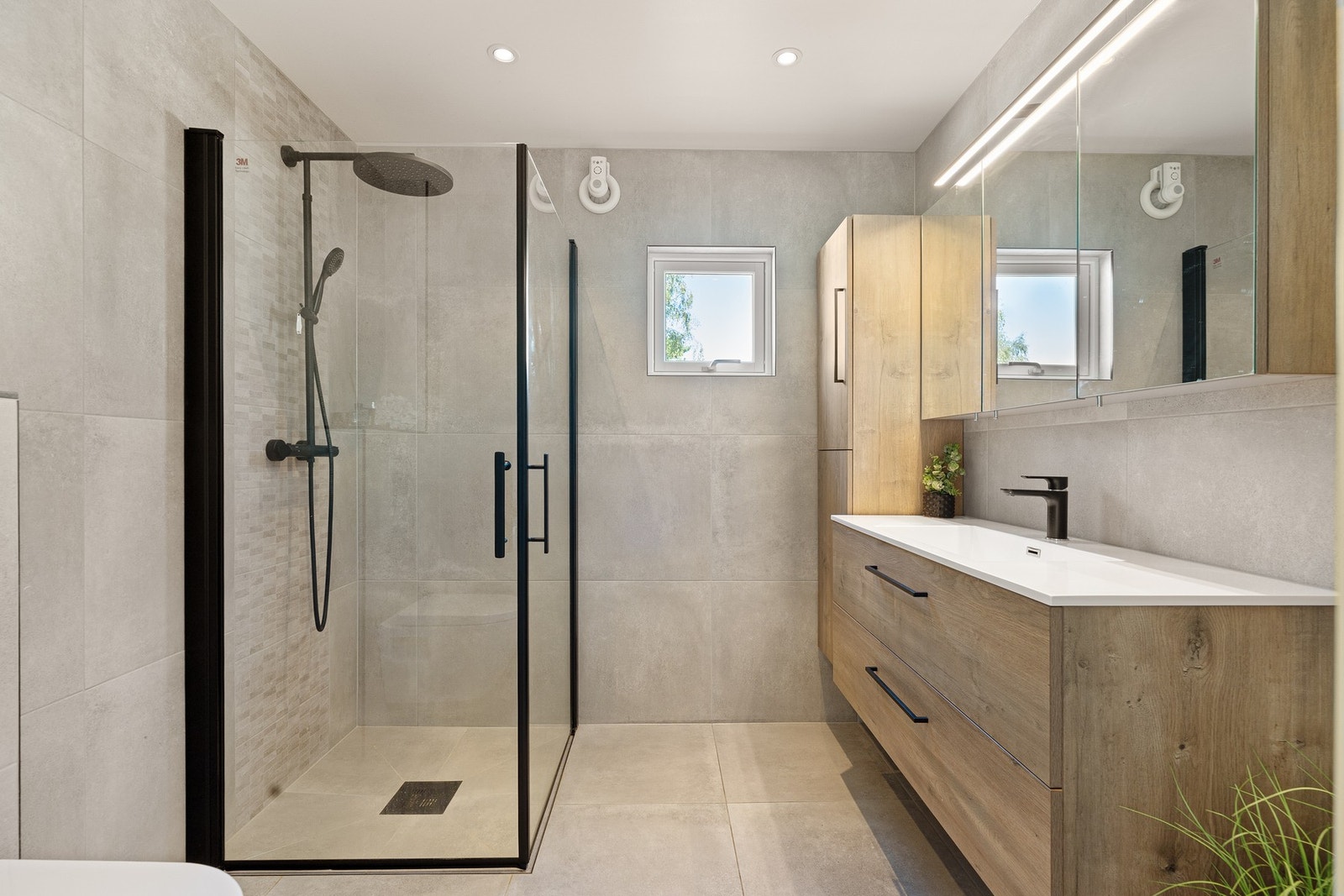 Flislagt bad med dusjhjørne, vegghengt klosett og moderne innredning - både lekkert og praktisk. Galleribilde