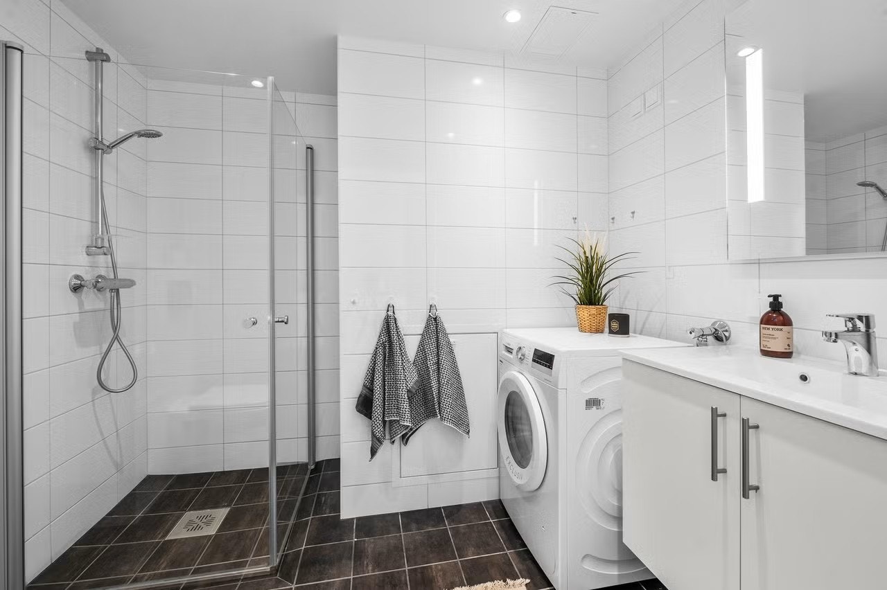 Romslig bad med innfellbare dusjvegger, vegghengt wc og servant med underskap. Galleribilde