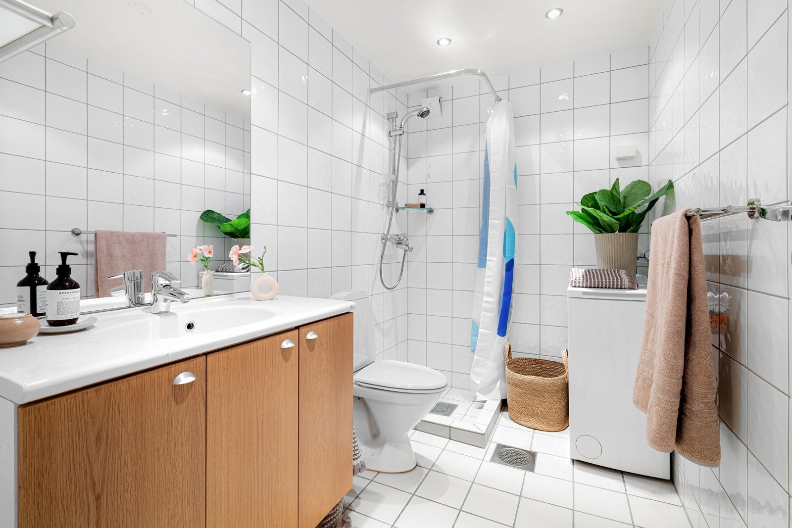 Baderommet er utstyrt med servantinnredning med speil over, dusjhjørne med forheng, gulvstående toalett og opplegg for vaskemaskin. Galleribilde