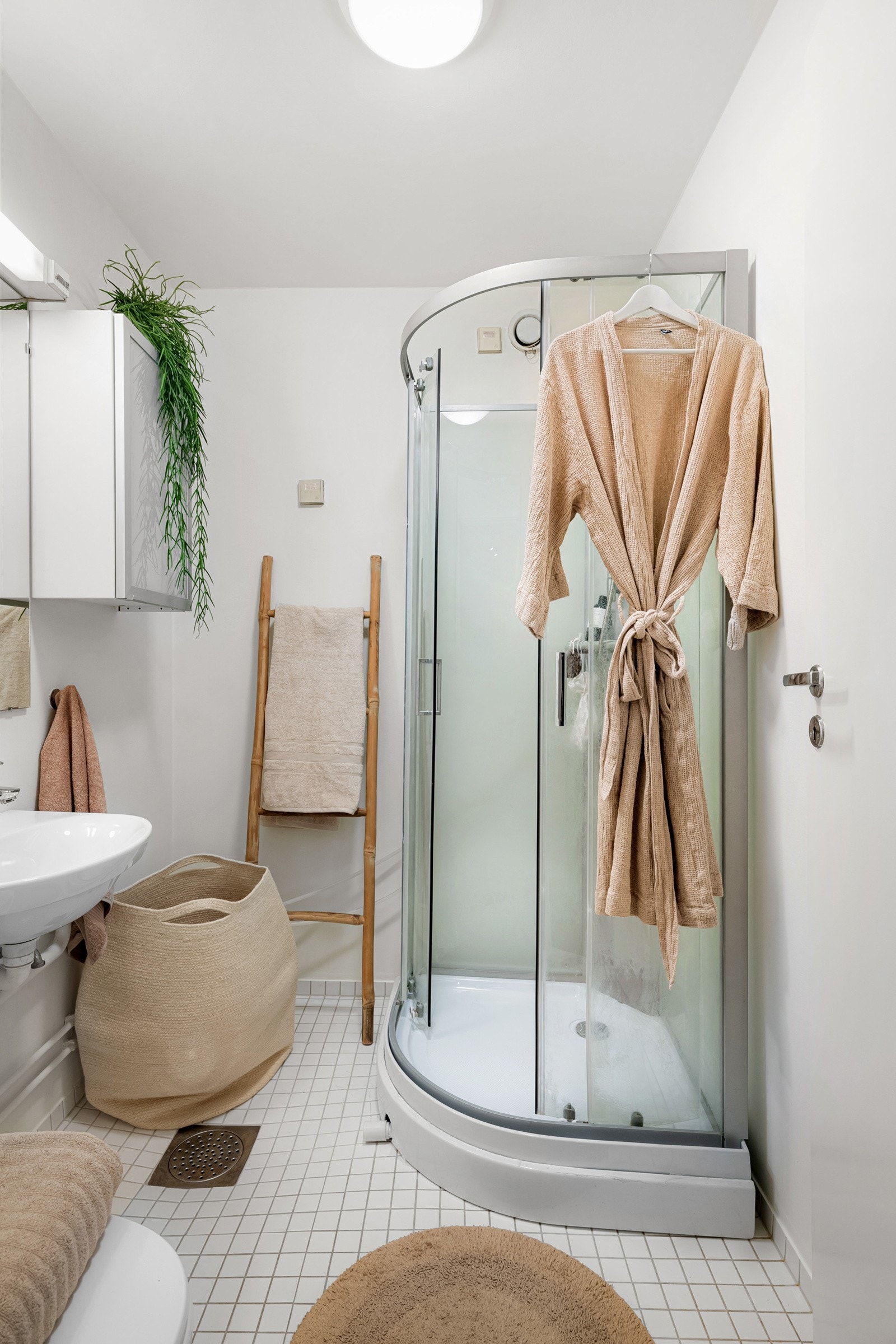 Eldre baderom i 4. etasje med flislagt gulv, lysmalte overflater og mekanisk avtrekk. I hjørnet er det plass og opplegg for vaskemaskin. Galleribilde