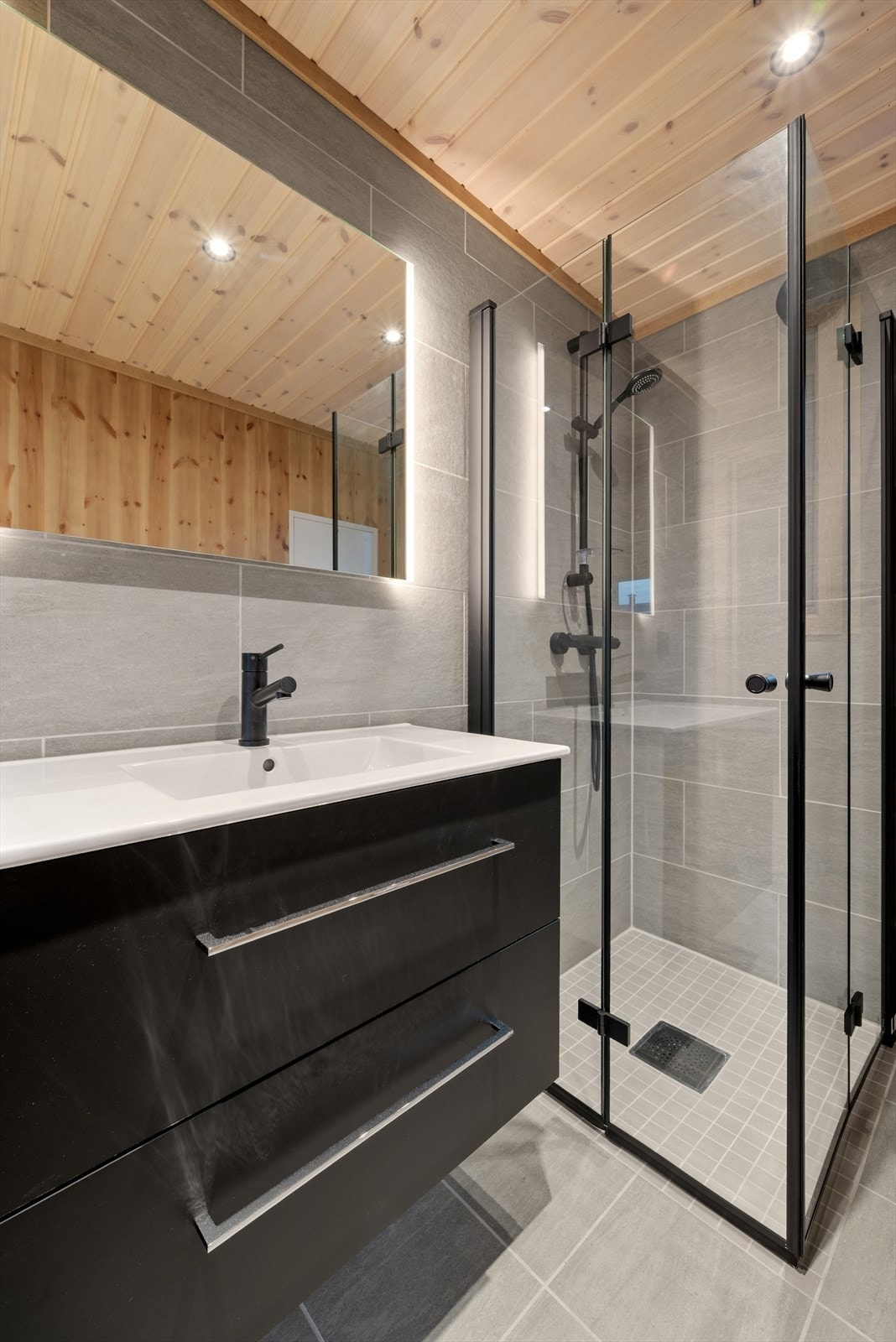 Badet har flotte, svarte detaljer som baderomsinnredningen, stikkontakter, i dusjsonen og ventilasjonen. Galleribilde