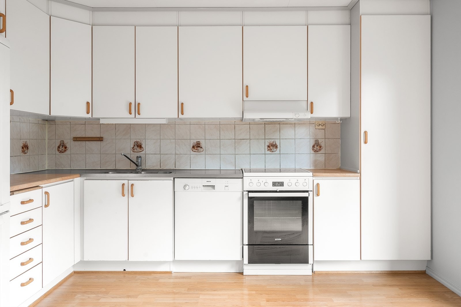 Oversiktlig kjøkken med oppvaskmaskin og effektiv ventilator over koketoppen. Galleribilde