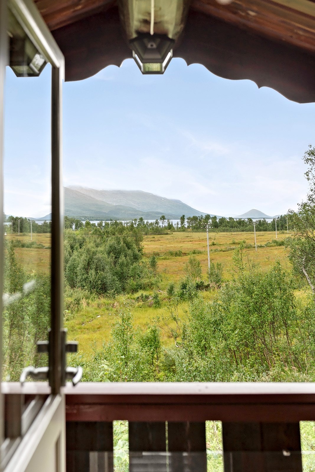 Utsikt. Her mot det grønnkledde landskapet, vannet og fjellene. Galleribilde