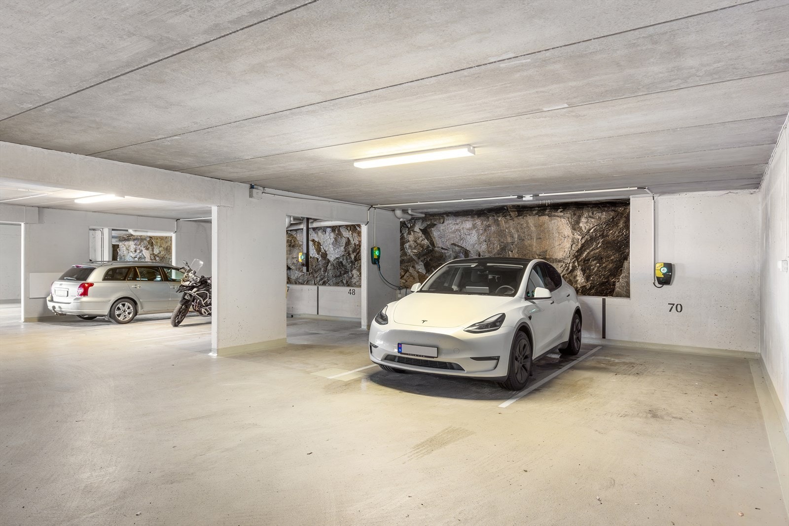 Det medfølger garasjeplass med lader for el-bil i lukket garasjeanlegg. I tillegg disponerer leiligheten en ekstra parkeringsplass side om side som leies av sameiet. Leien for denne plassen er i dag inkl. i felleskostnadene. Galleribilde