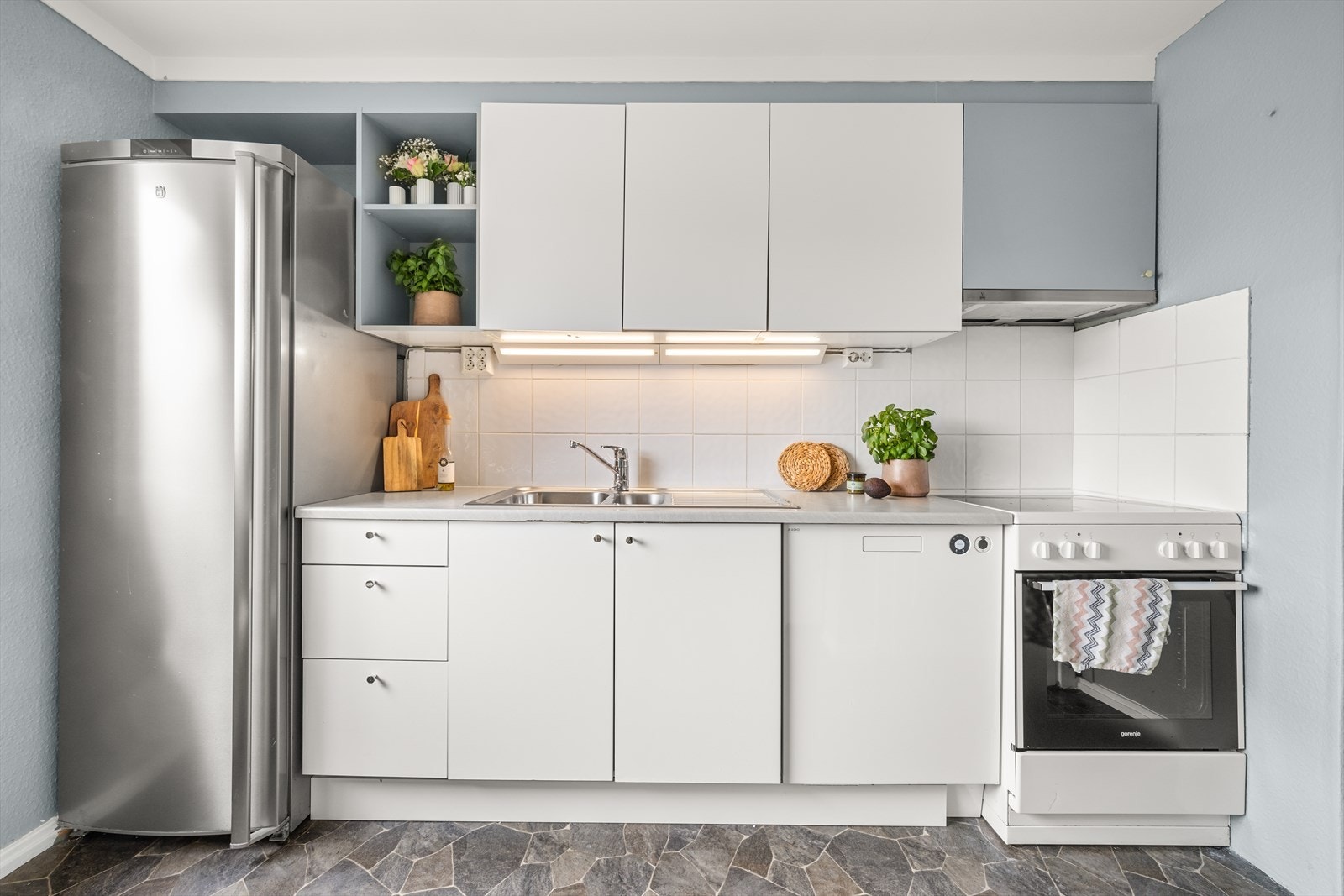 Praktisk kjøkken med glatte fronter og flis over kjøkkenbenk Galleribilde